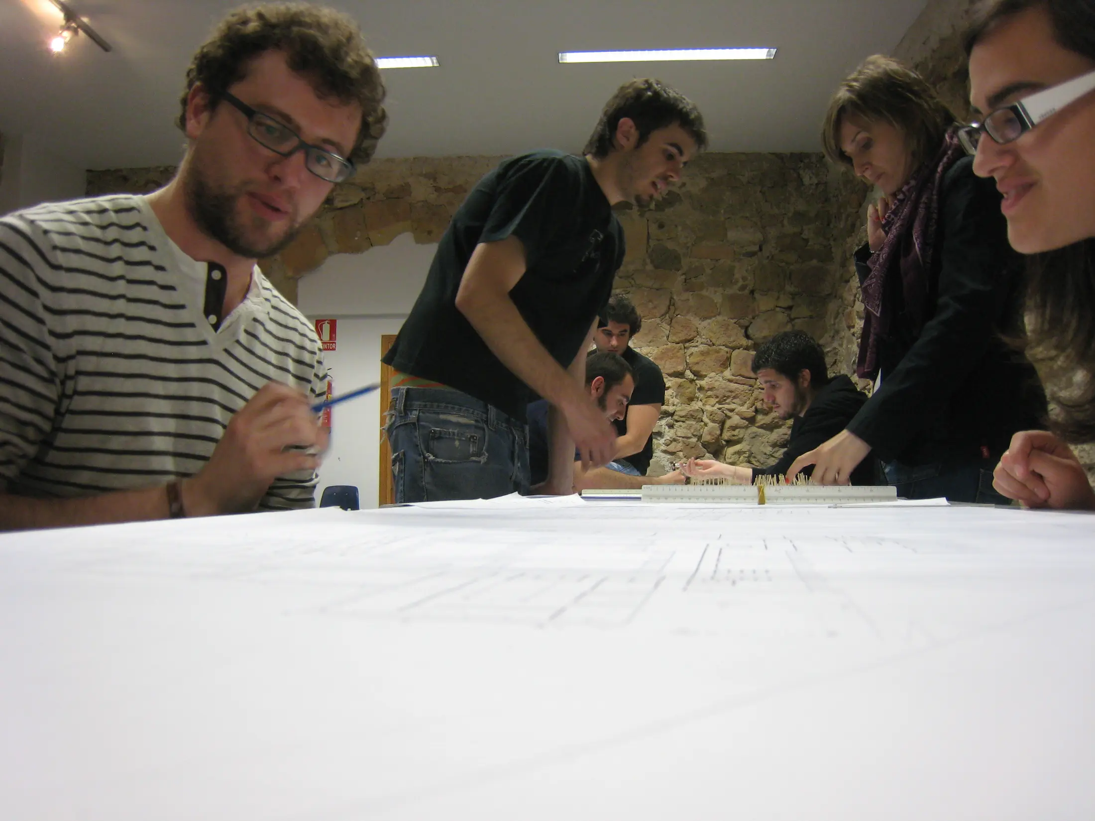 Estudiantes trabajando juntos alrededor de los dibujos de un proyecto